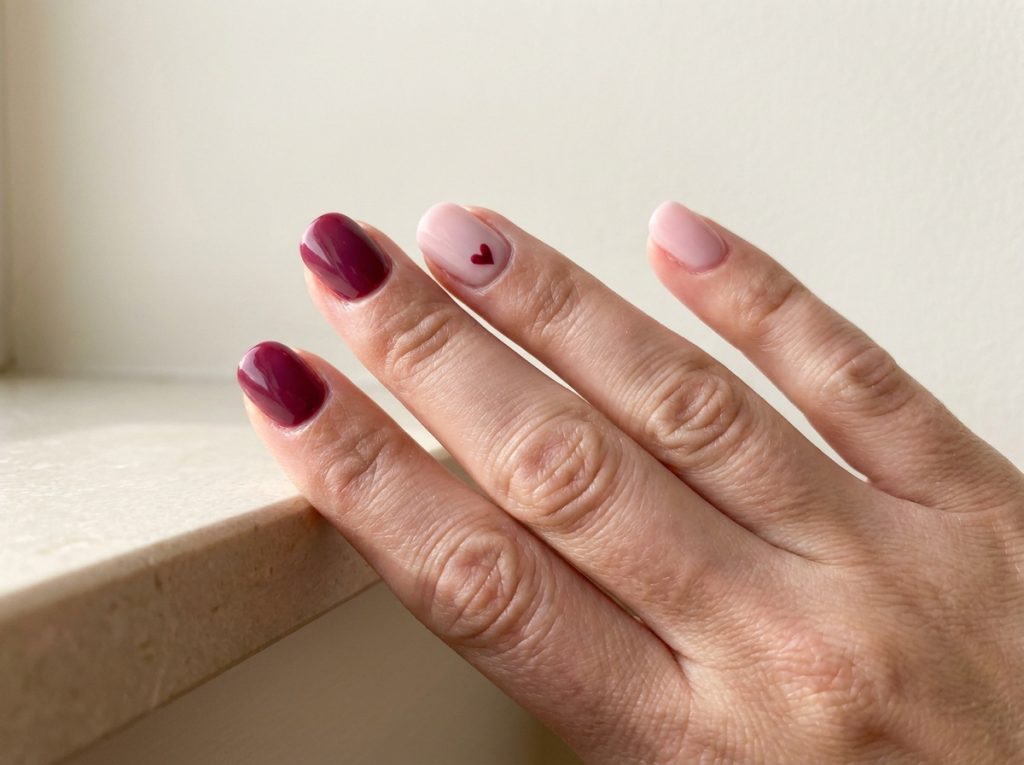 One tiny berry heart ties together a berry and pale-pink manicure.