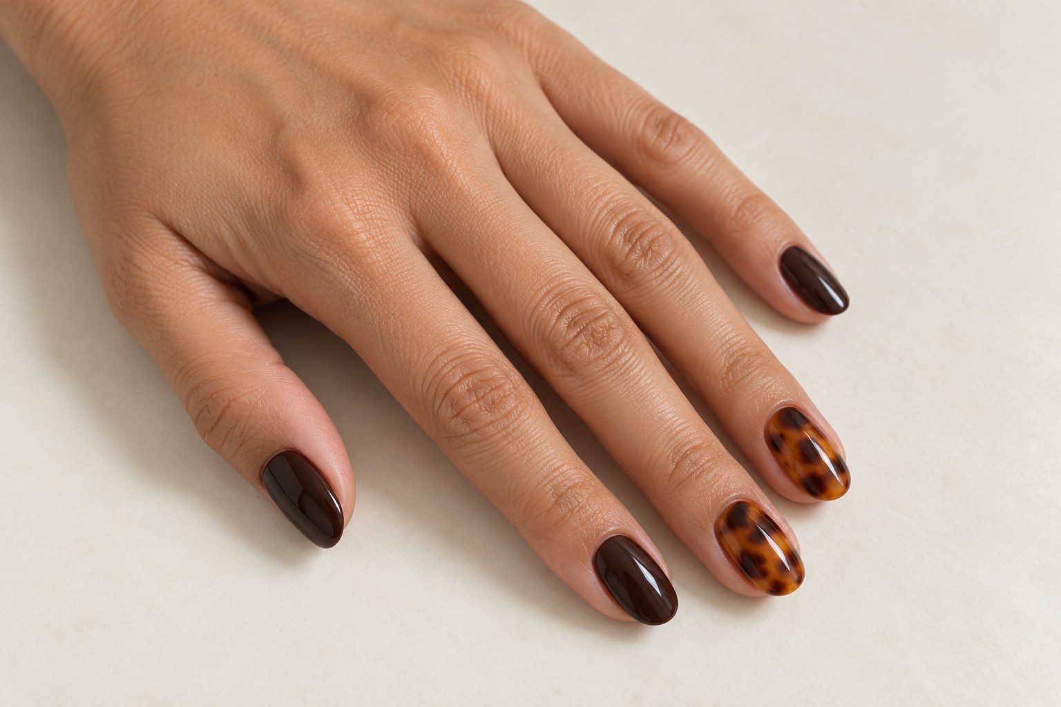 Amber tortoiseshell accent nails with irregular brown patches beside glossy espresso nails.