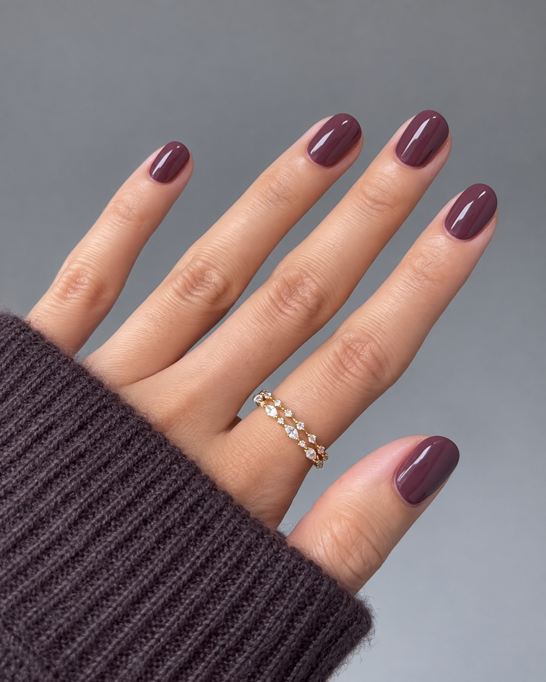Short oval nails with glossy muted plum polish.