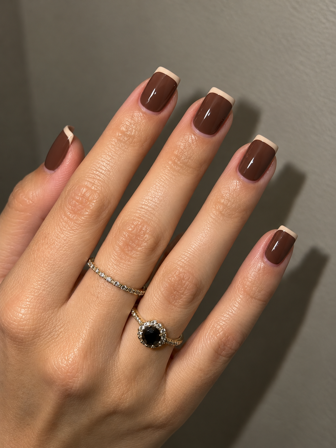 Short mocha-brown nails with narrow almond-cream French tips.