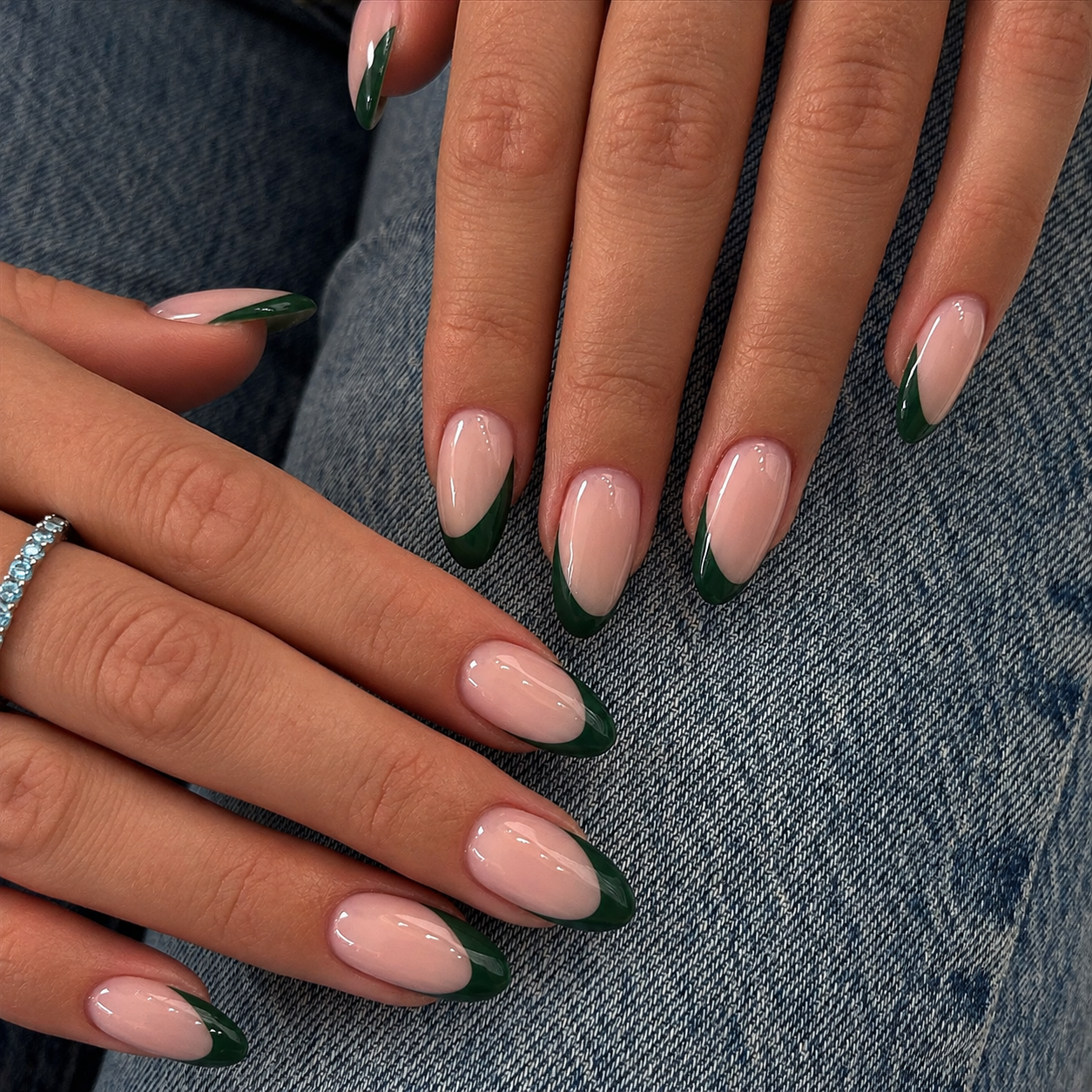 Almond nails with nude bases and asymmetrical forest-green tips.