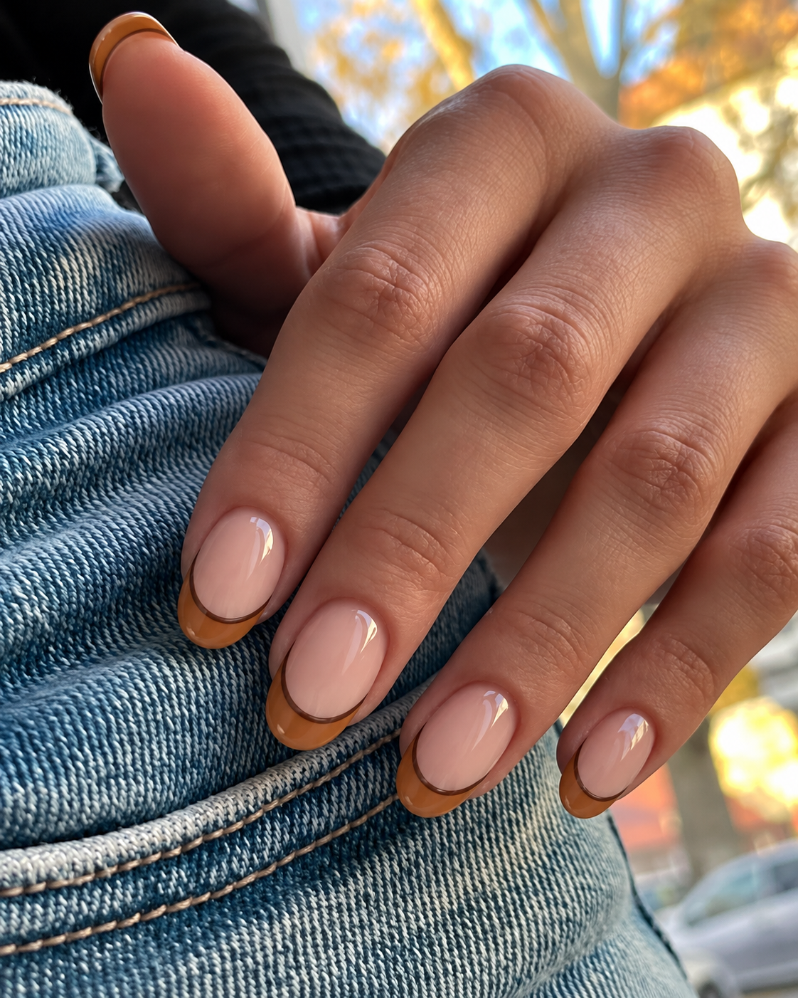 Oval beige nails with caramel tips outlined in cocoa brown.