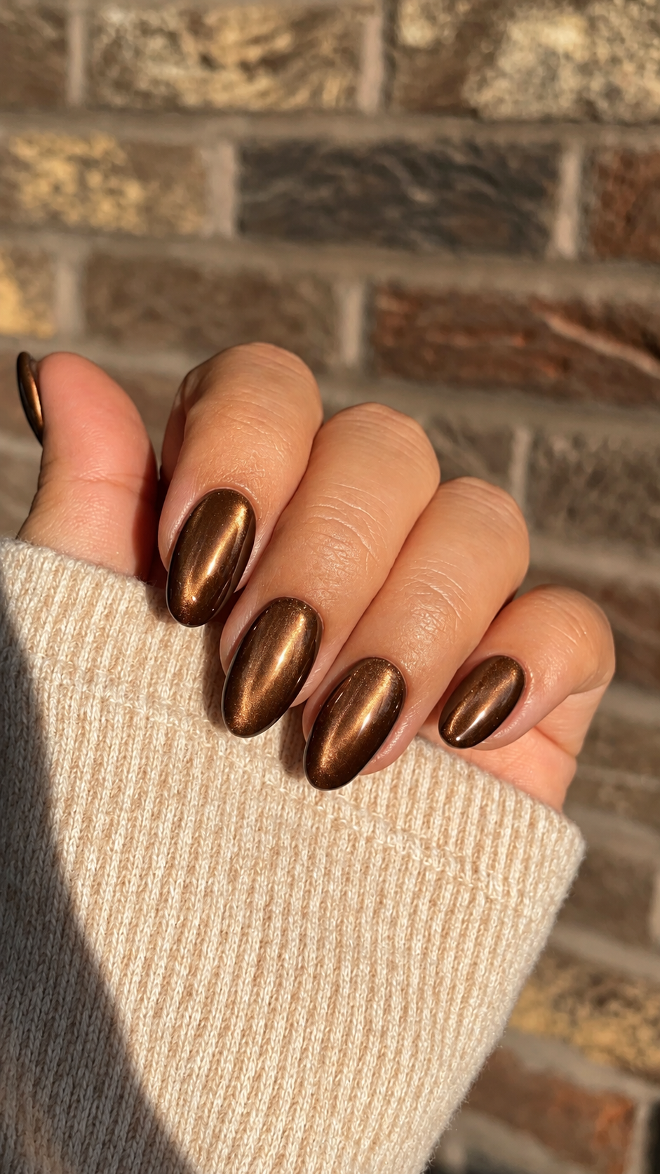 Oval nails with warm hazelnut-brown chrome polish.