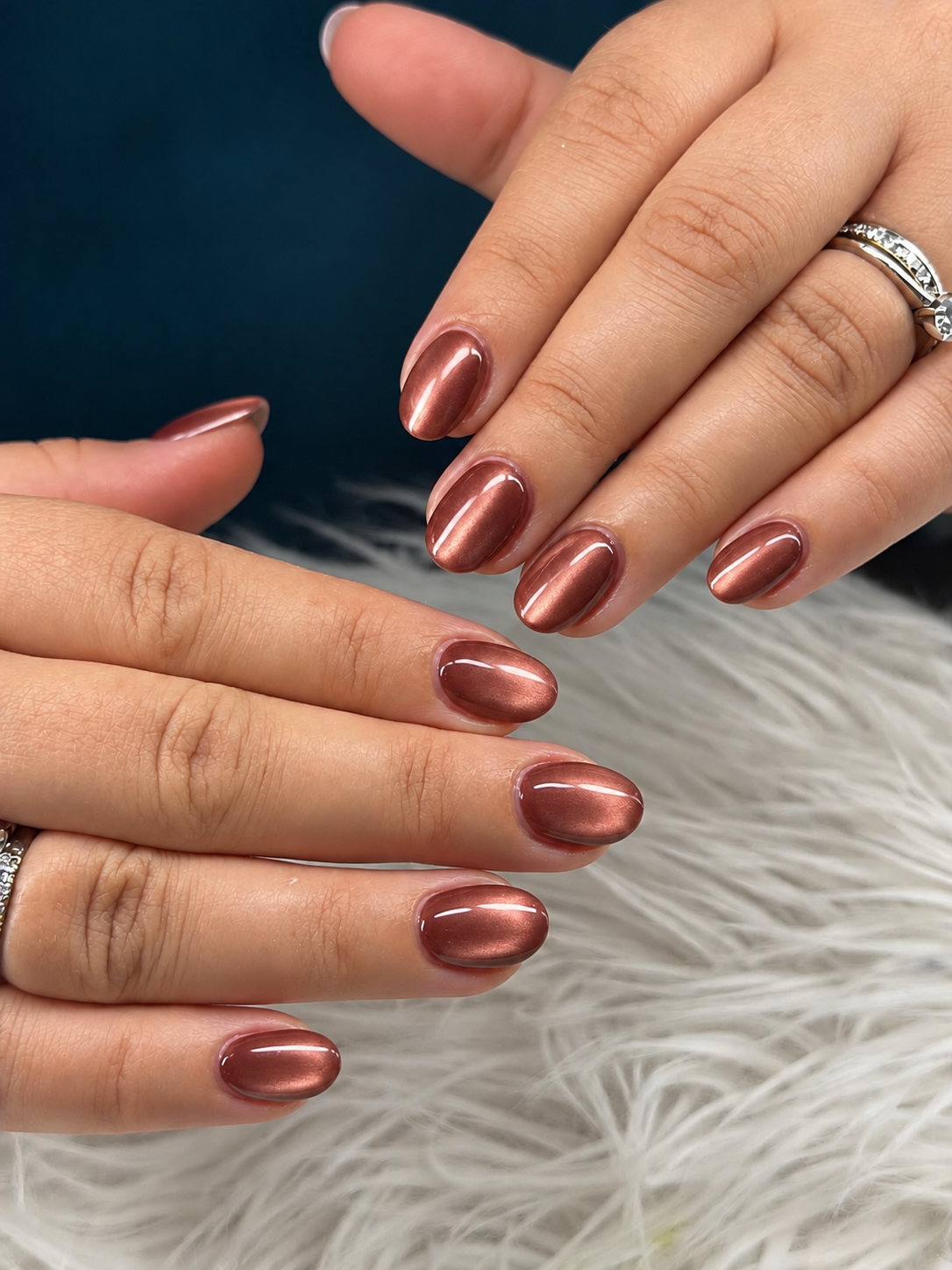 Short oval nails with a smooth copper-rose metallic finish.