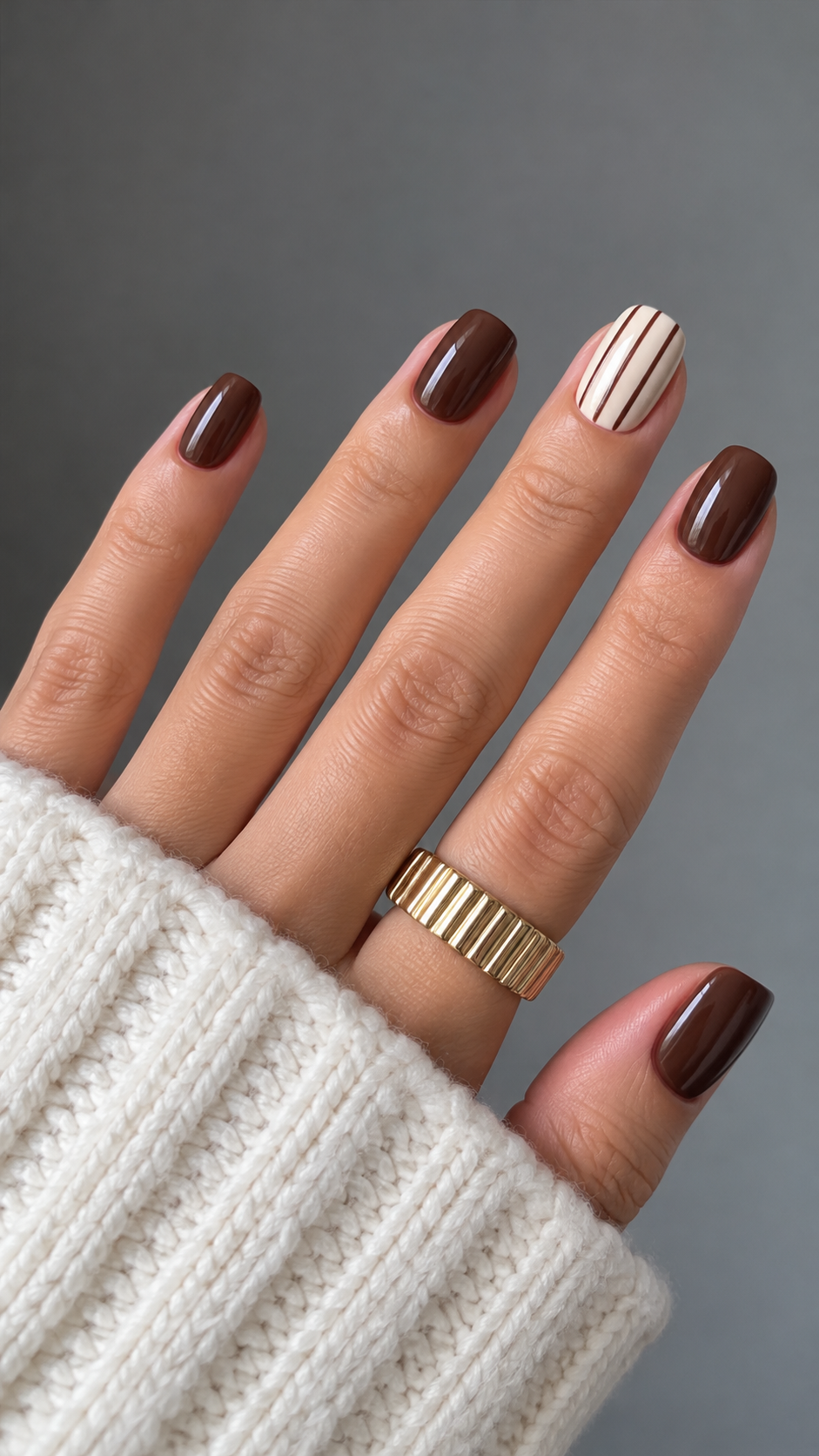 Cocoa nails with a cream ring-finger accent bearing three fine brown pinstripes.
