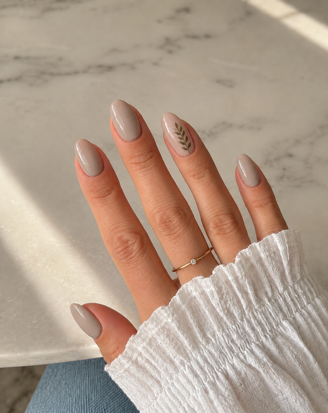 Mushroom-beige nails with one fine olive sprig on the ring finger.