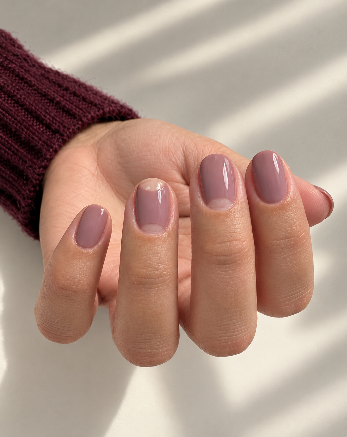 Dusty-mauve nails with clear half-moons on the middle and ring fingers.