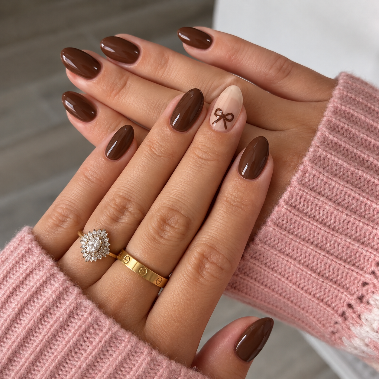 Cocoa nails with a small painted bow on a sheer beige ring-finger accent.