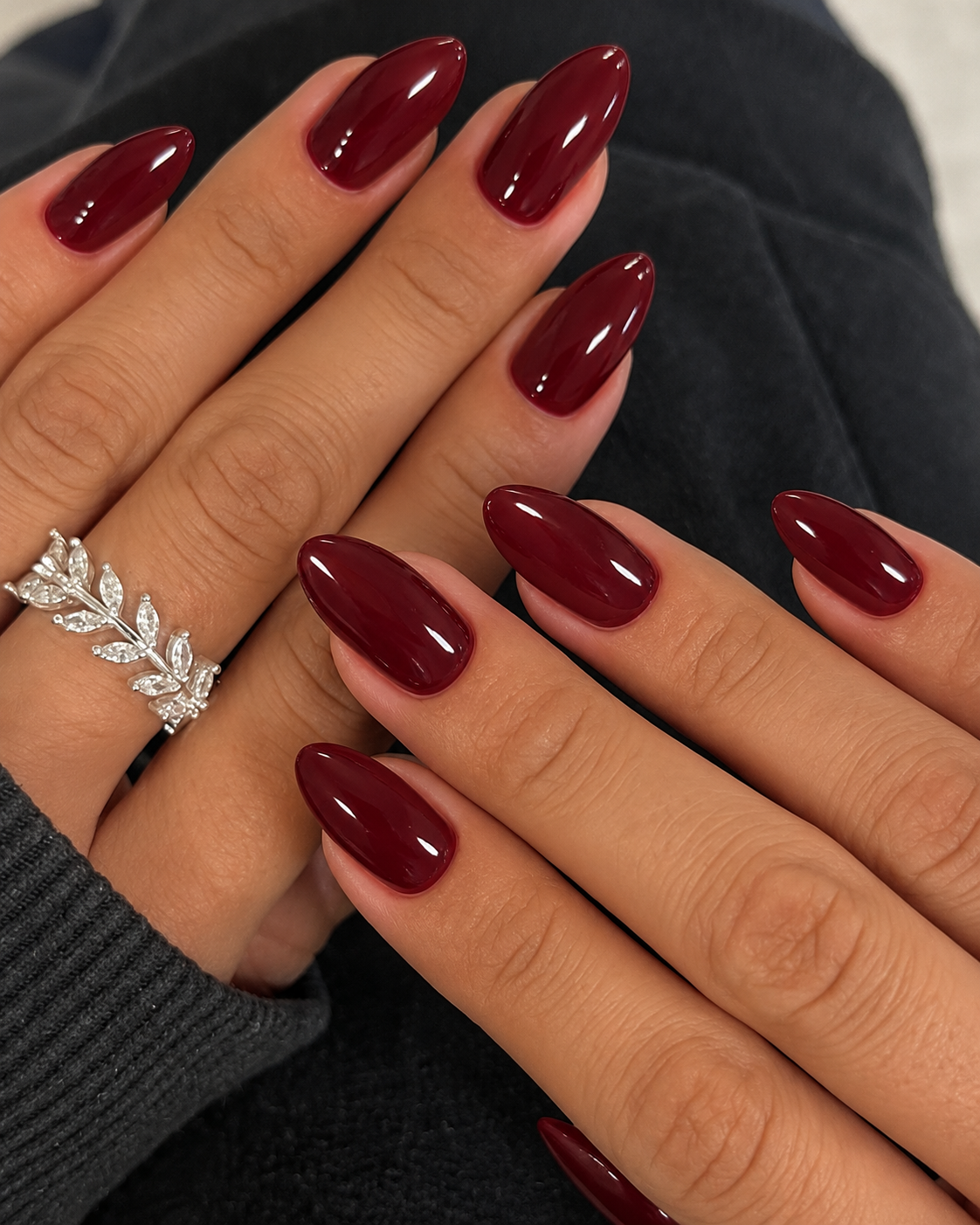 Short-to-medium oval nails painted opaque deep oxblood with a glossy finish.