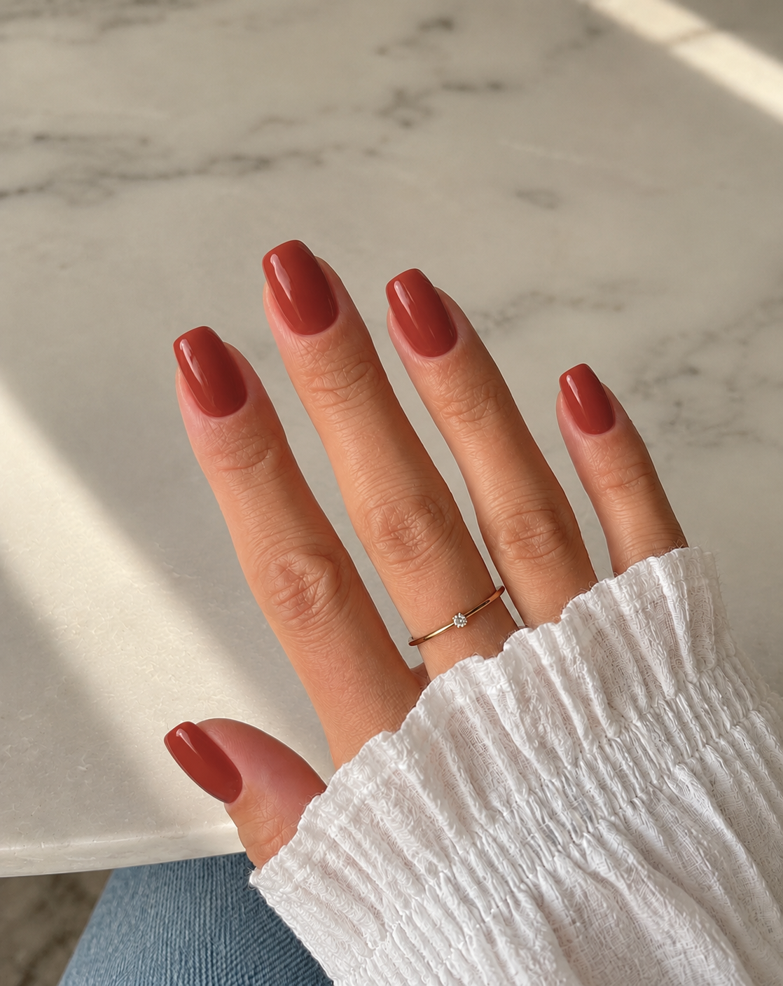 Short soft-square nails painted glossy maple-brick red with terracotta undertones.