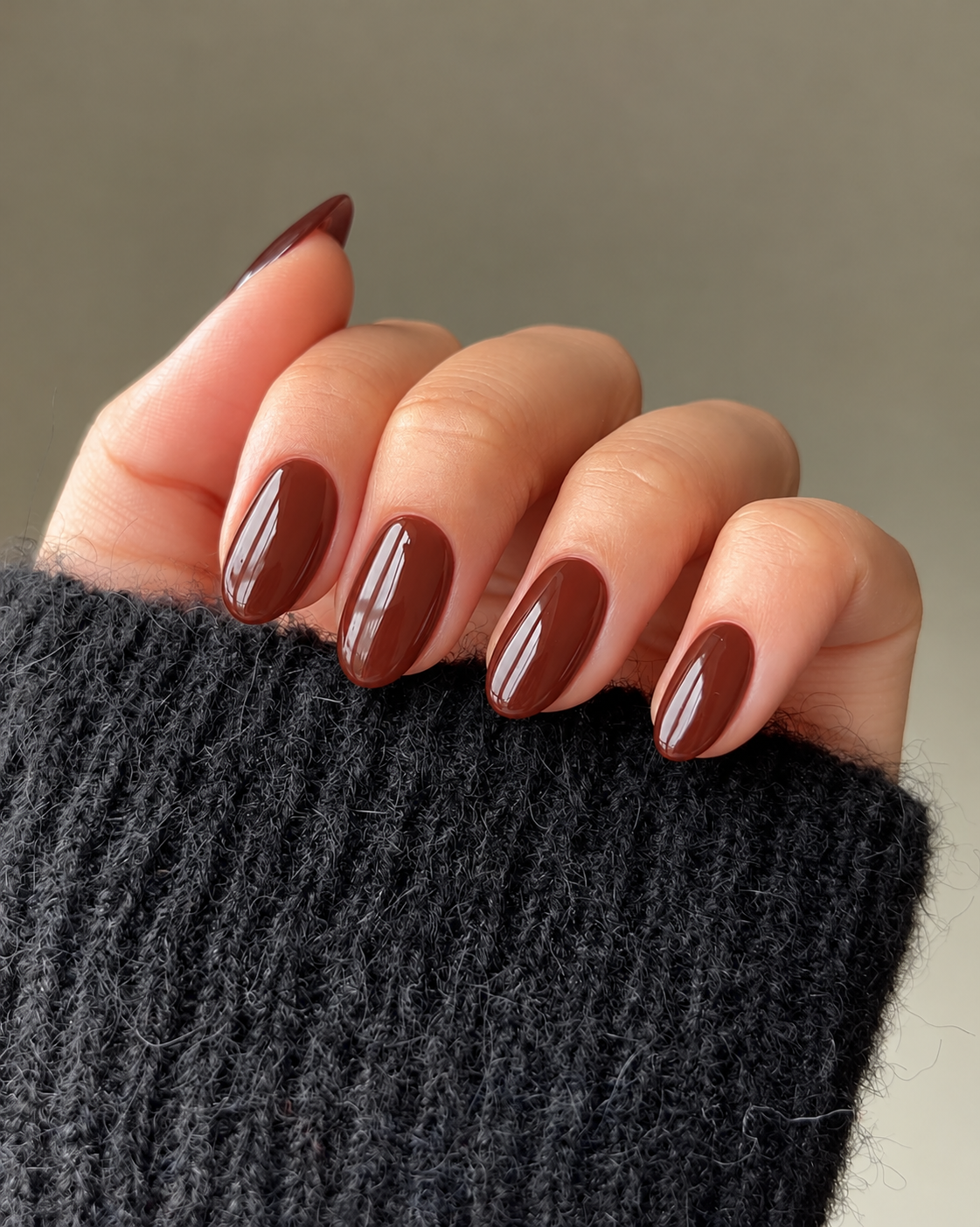 Short rounded nails painted glossy reddish chestnut brown.