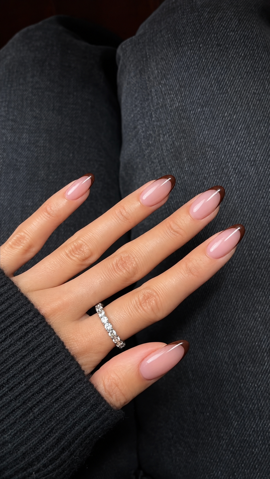 Short rounded nails with rosy translucent bases and thin chocolate French tips.
