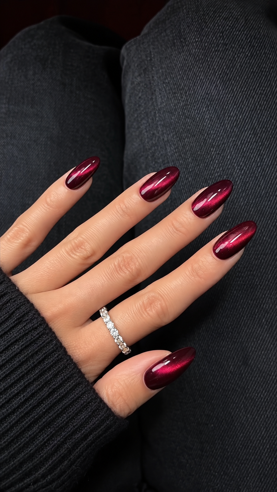 Short rounded-square cranberry nails with a diagonal pink-red cat-eye light band.