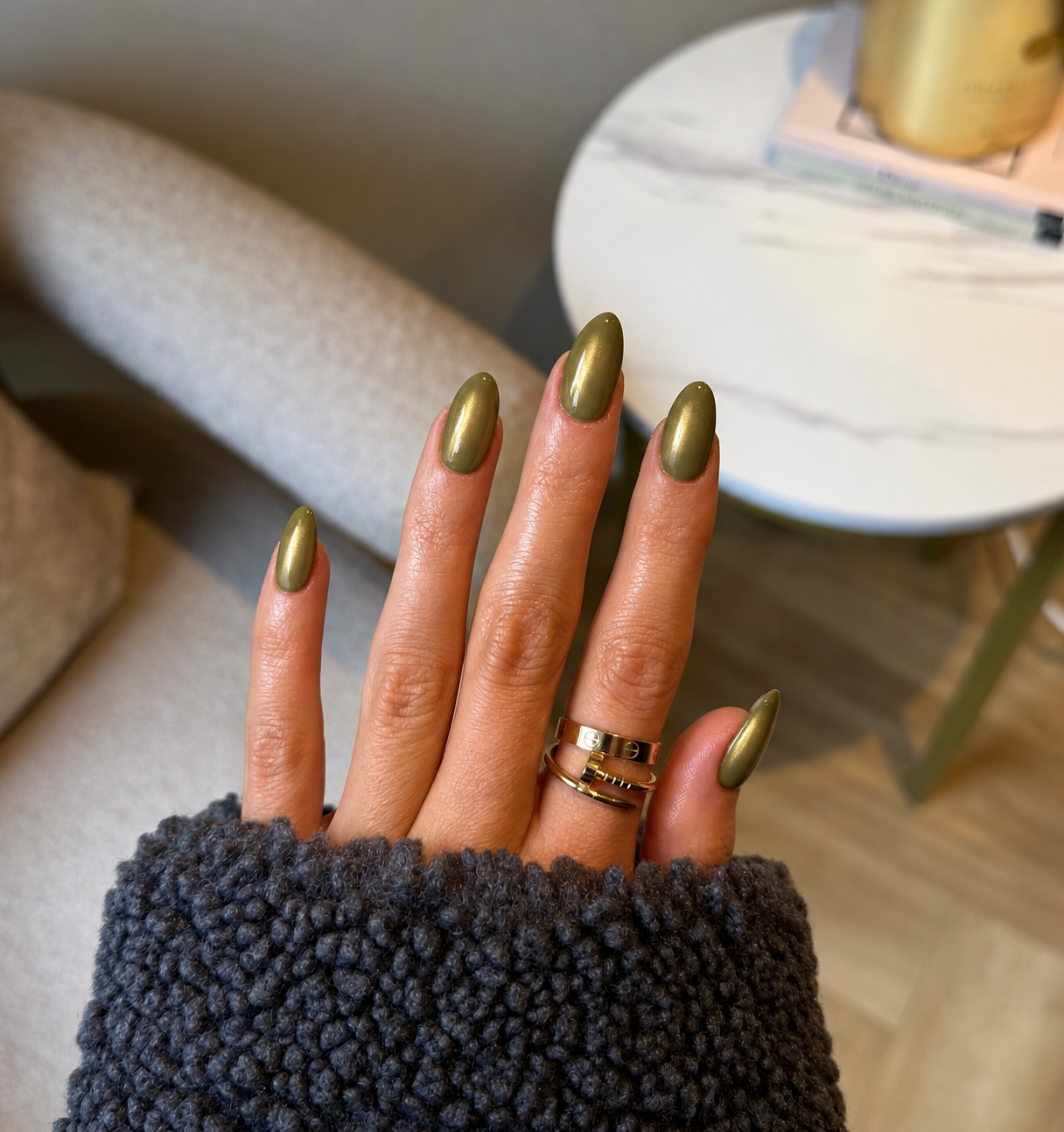 Muted olive oval nails with a fine golden pearl sheen.