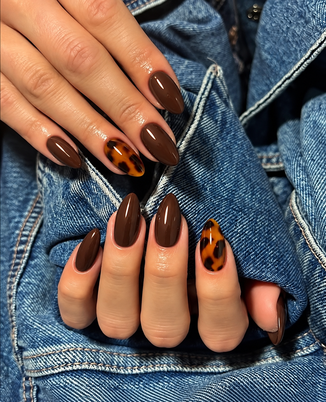 Glossy cocoa nails with an amber and dark-brown tortoiseshell ring-finger accent.