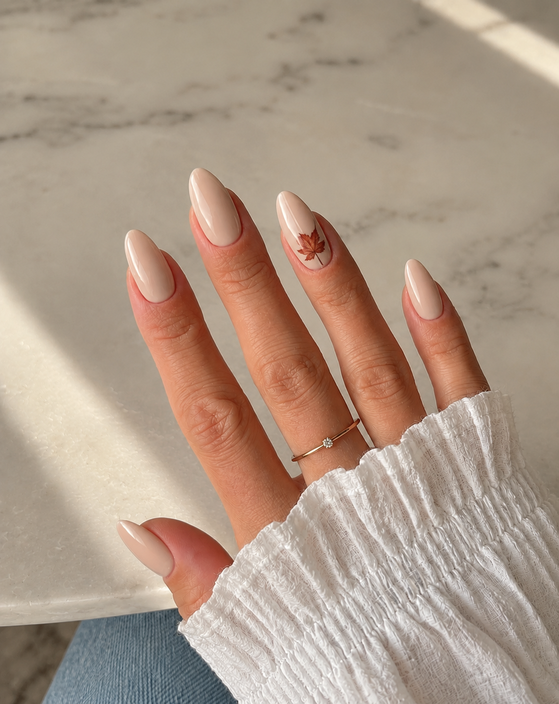 Short glossy oat nails with one small russet leaf on the ring finger.