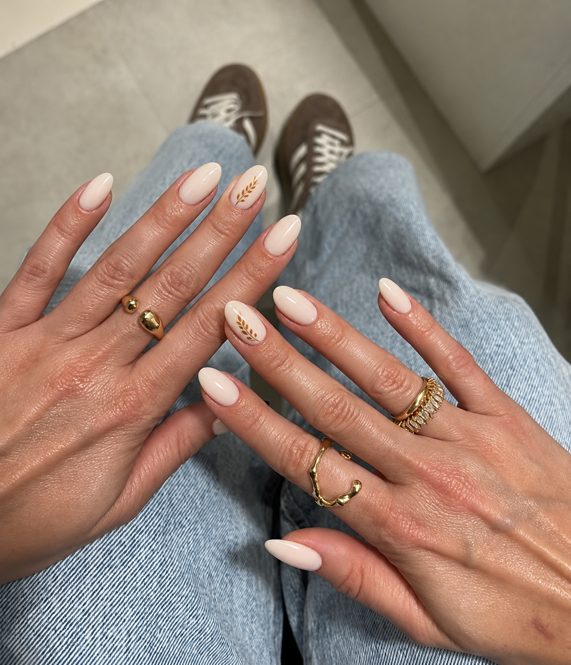 Warm ivory nails with a single fine ochre wheat stalk along the side of the ring-finger nail.