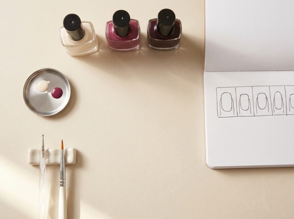 Polish, a dotting tool, a brush and a simple nail plan are arranged before painting.